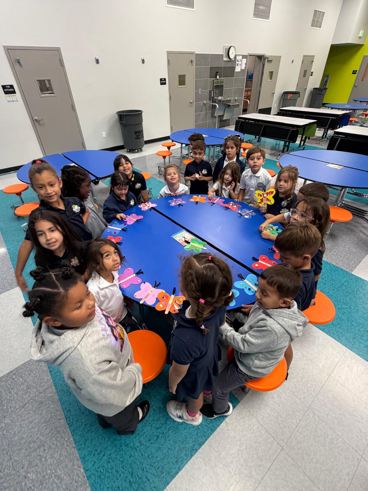 YMCA students gathered around a table displaying colorful butterfly art projects